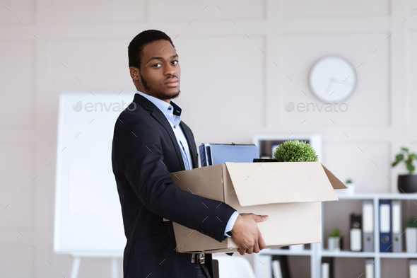 Young black man got fired, holding box with his belongings