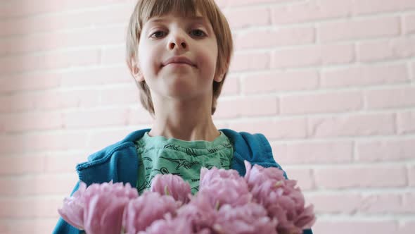 Portrait Of A Child With A Bouquet Of Flowers In His Hands. Close-up. alt