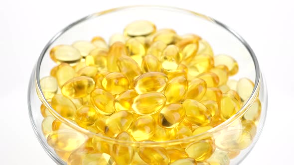 Capsule of Omega 3 in clear bowl rotation on white background. Omega 3 gold fish oil capsule alt