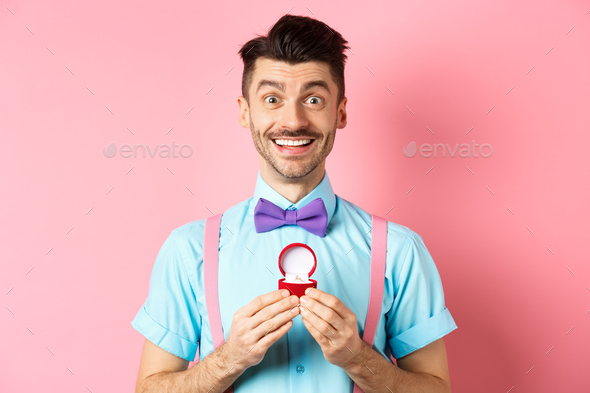 Valentines day. Romantic man in bow-tie showing engagement ring and smiling, asking to marry him