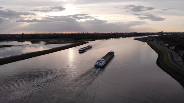 An Empty Barge Ship Passes To A Tanker Sailing On Inland Waterway During Sunset. - Aerial Shot alt