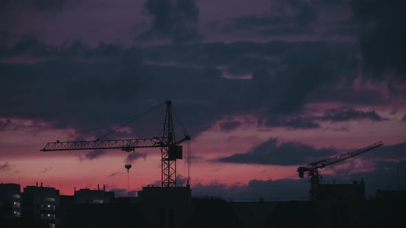 Cranes on Construction Site Under Grey Cloudy Sky. Beautiful sunset. Timelapse.