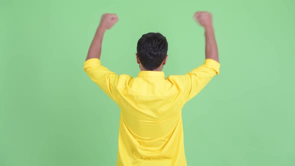 Rear View of Happy Young Hispanic Businessman with Fists Raised alt