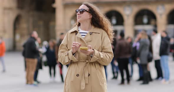 beautiful young woman with long curly hair is wearing sunglasses and using cellphone. 