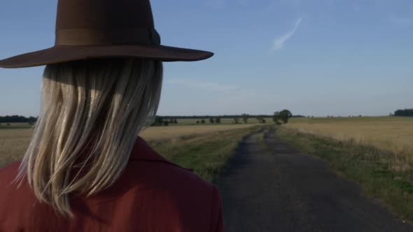 Girl in vintage hat red dress on country road in sunset