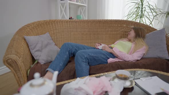 Wide Shot Hysterical Crying Millennial Woman with Tissue Lying on Couch Talking alt