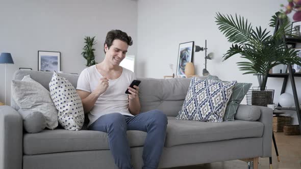Excited Man Celebrating Success, while Using Smartphone alt