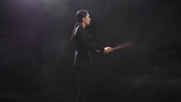 Side View Of Asian Conductor Woman Holding A Baton And Showing Gesture Quickly In The Black Studio alt