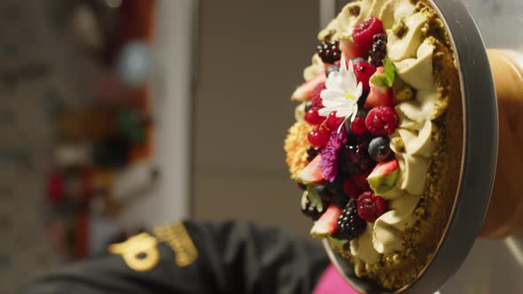 Decorated red fruit pie rotating on table. Patisserie scene. Vertical, close up alt