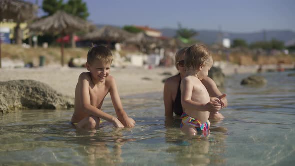 Mom with Two Children Bathe in the Clear Sea Water. Morning Croatia