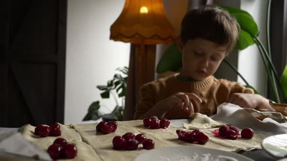little boy cooking cookies with a cherry at home.