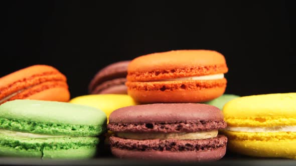 Colorful Macaroons are rotating on a black dish