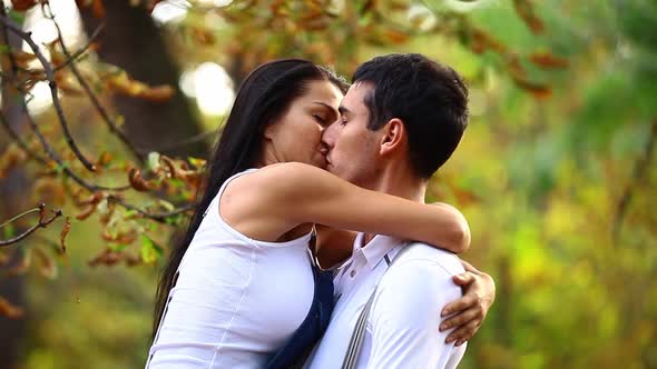 Teen couple kissing in the park in autumn time