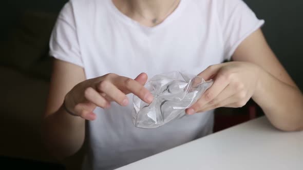 Young Woman is Showing Plastic Bottle for Recycle While Sitting at Table in Home Iroi alt