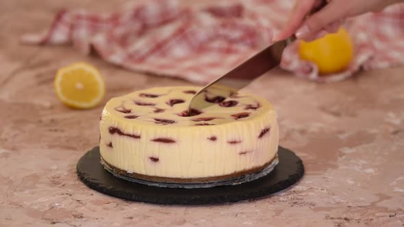 Pastry chef cuts cherry cheesecake.