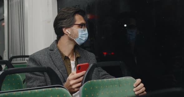 Crop View of Man in Medical Mask and Glasses Using Smartphone alt
