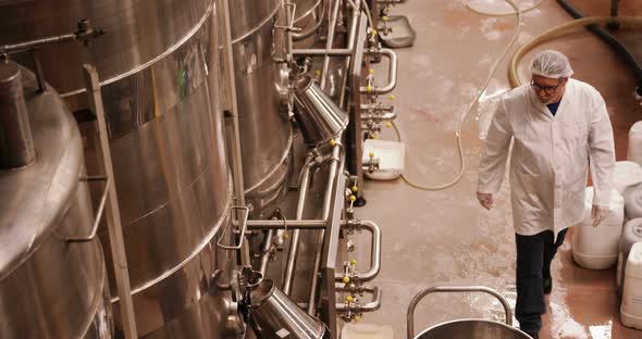 Factory worker examining storage tanks alt