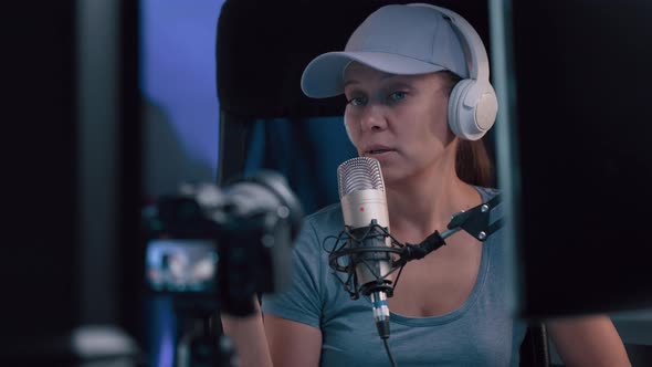 Beautiful Woman In A Cap And White Headphones Leads A Live Stream alt