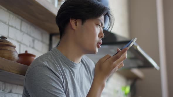 Side View of Confident Asian Man Talking at Smartphone Speakerphone in Slow Motion alt