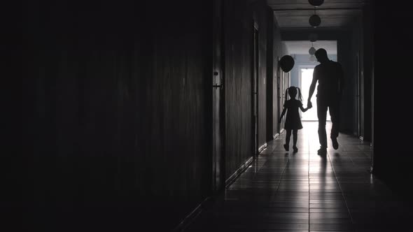 Silhouettes of Father and Girl with Balloon Walking along Hallway