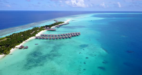 Paradise tropical island with rows of bungalows entering on quiet turquoise lagoon around white sand alt