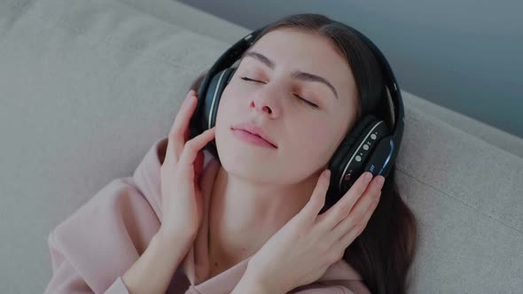 Caucasian young woman wearing headphones, listening to music and relaxing
