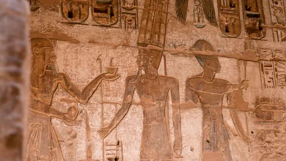 Detail of ancient Egyptian hieroglyphs of people and god on a wall, Habu Temple, Luxor, Egypt. alt