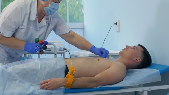 Nurse performing electrocardiography on a male patient alt