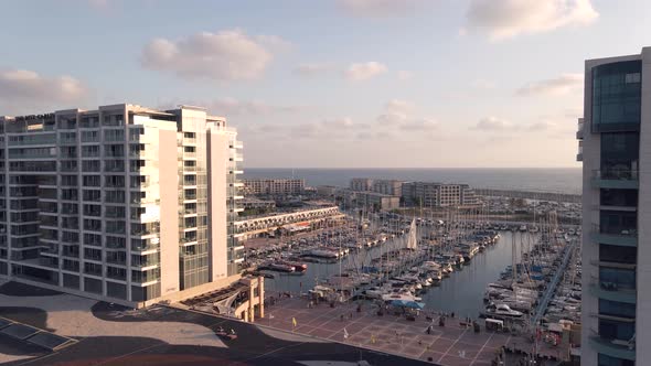 Aerial view of the harbor with boats and tall buildings in Herzelia in summer at sunset alt