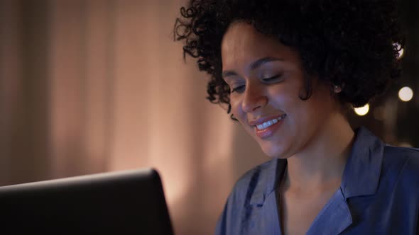 Happy Woman with Laptop Sitting in Bed at Night