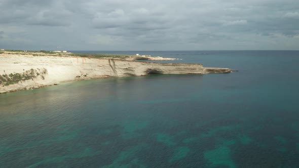 AERIAL: Ta Kalanka Sea Cave on Stormy Cloudy Sky and Beautiful Turquoise Color Water