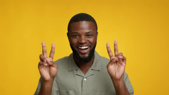 Funny Cheerful Black Guy Showing Peace Gesture At Camera With Two Hands alt