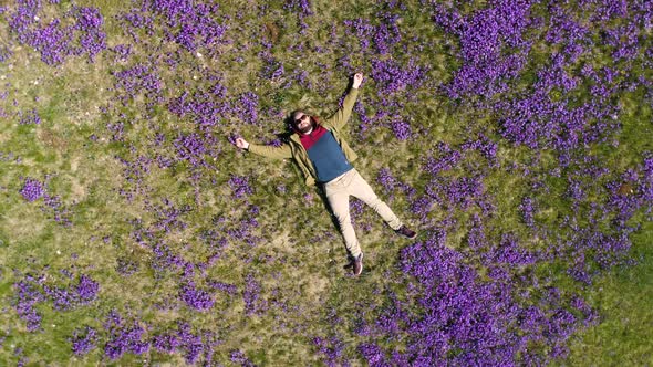 Bearded Man Lies on the Field in Violets Top-down View