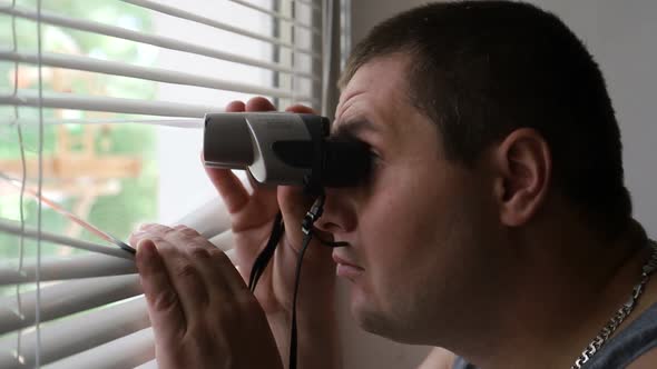 Man Spying on People Using Binoculars for Observation alt