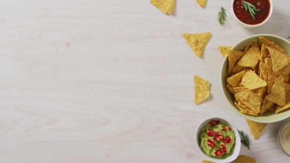 Video of tortilla chips, guacamole and salsa dip on a wooden surface alt