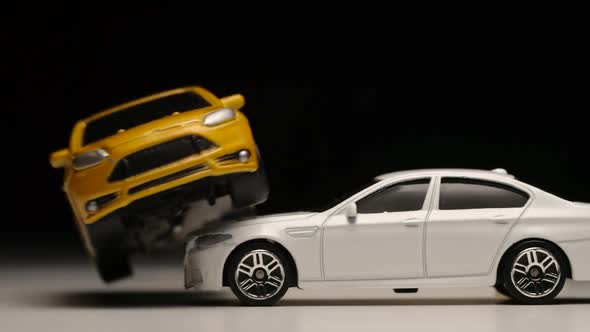 Yellow toy car jumps across a white toy car