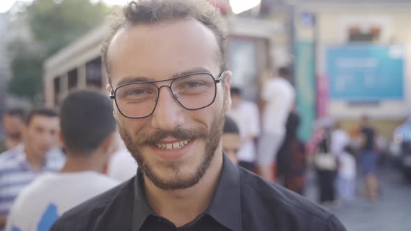 Laughing teenager looking at camera among crowd. alt