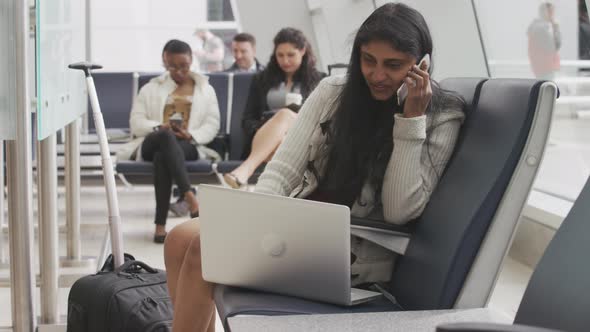 Woman talking on cell phone an using laptop at airport