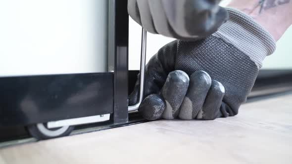 Master with Special Screwdriver Adjusts Sliding Doors of Wardrobe alt