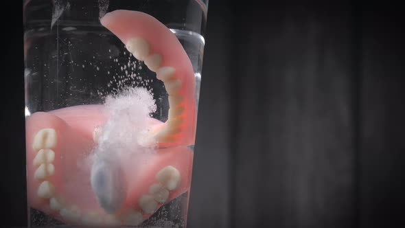 Closeup Shot of a Prosthesis Teeth Cleaner Tablet Dropped Into a Glass of Water