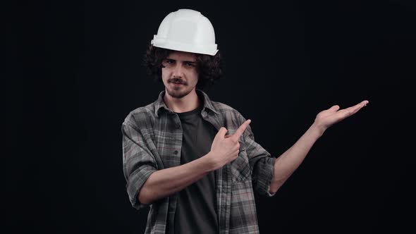 Charismatic Hipster Looks with His Hand on the Left Side and Recommends Buying with a Smile alt