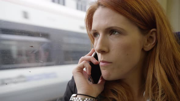 Commuter on her way to work looking out of the window and using smart phone