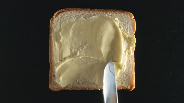 Human hand spreads a butter on a bread
