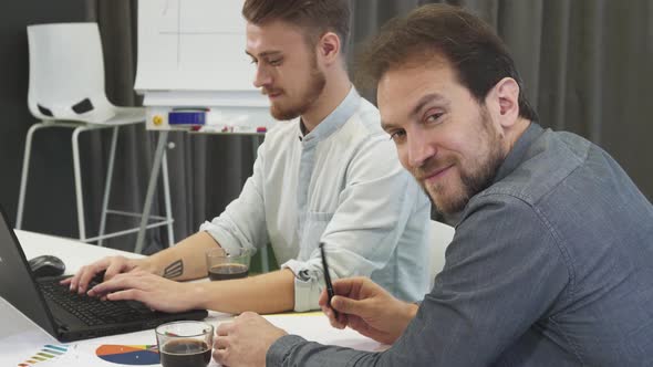 Mature Businessman Smiling To the Camera While Working at the Office alt