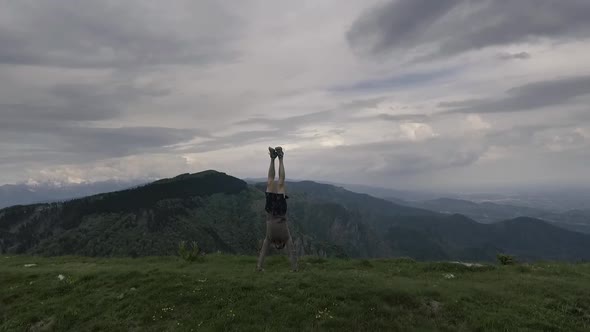 Man doing a handstand outdoors on a cliff