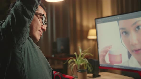 Male Digital Editor Stretching While Works In Photo Editing Software On His Personal Computer alt