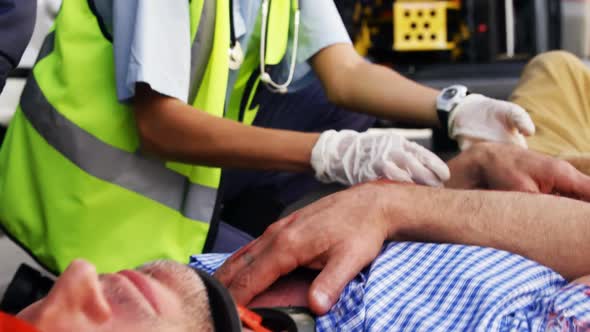 Emergency medical technician taking the pulse of his wounded person alt