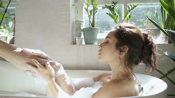 Woman washing legs in the bathtub.