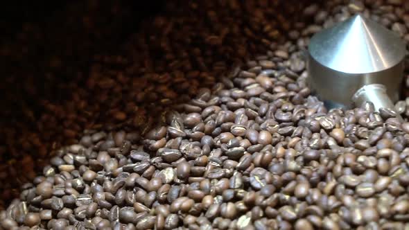 Coffee bean roaster mixing and turning the grains with steel arms, Handheld close up shot alt