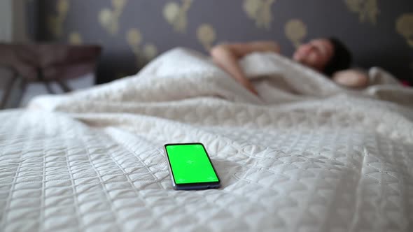 Girl turns off the alarm on the phone with a green screen alt